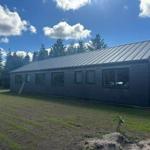 Moderne Hütte mit Metalldach und großen Fenstern im Wald