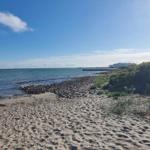 Strand mit Sand und Steinen, Blick auf das Meer und ein Schiff im Hintergrund.
