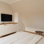 Schlafzimmer mit Bett, TV und Holzregal an der Wand