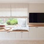 Blick auf Fensterbank mit Kissen und TV-Wand.