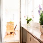 Blick auf Balkon mit Holzstuhl. Fensterbank mit Lavendel und Blumen.