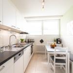 Küche mit Arbeitsplatte, Spüle und Essbereich mit Tisch und Stühlen.