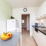 Küche mit Arbeitsplatte, Spüle, Kühlschrank und Obst auf Tisch.