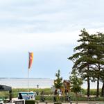 Wasserufer mit Baumreihe und Flagge im Hintergrund