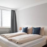 Ein Schlafzimmer mit Doppelbett, zwei Nachttischen und einem Fenster mit Jalousien.