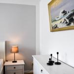 Schlafzimmer mit Bett, Nachttisch, Schrank und Wandbild mit Meeresmotiv.