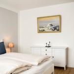 Schlafzimmer mit Bett, Nachttisch und Wandbild an der Wand.