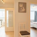 Haus mit Küche, Schlafzimmer und Stuhl im Flur. Wandbild mit zwei Vögeln.