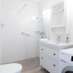 Badezimmer mit Dusche, Waschbecken und Waschmaschine.