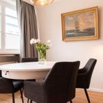 Rundtisch mit vier Stühlen, Wandbild und Stehlampe in einem Raum mit Fenster und Vorhängen.