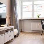 Wohnzimmer mit Fernseher, Fenster und Esstisch.