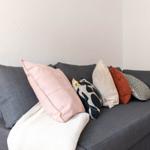 Graße Couch mit mehreren Kissen und einer Decke.