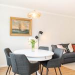 Essbereich mit runder Tisch und vier Stühlen. Wohnbereich mit Sofa und Kissen.