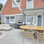 Terrasse mit Sitzgruppe, Esstisch und Grill. Modernes Design mit Holz- und Stoffmöbeln.