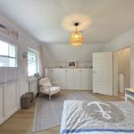 Schlafzimmer mit Bett, Nachttisch, Stuhl und Fenster. Deckenleuchte und Schrank sind sichtbar.