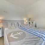 Schlafzimmer mit Bett, Nachttisch und Regal. Dekoration mit Ankern und Streifen.
