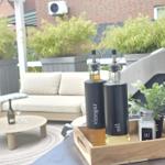 Auf der Terrasse stehen Öle und Essig in Flaschen mit Salz- und Pfefferstreuer.