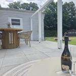 Auf der Terrasse steht ein Tisch mit einer Flasche Prosecco und Gläsern. Im Hintergrund ein weißes Haus mit Garten.