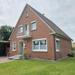 Zweistöckiges Haus mit Balkon, Eingangstreppe und Garten.