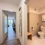 Badezimmer mit Toilette und Waschbecken. Durchgang zur Wohnung mit Holzboden.