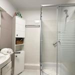 Badezimmer mit Dusche, Waschbecken und Aufbewahrungsmöbel.