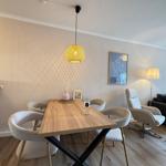 Essbereich mit Holztisch und Stühlen, hängende Lampe und Wohnbereich mit Sofa.