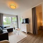 Wohnzimmer mit Sofa, Fernseher und Balkonansicht.