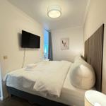 Schlafzimmer mit Bett, Fernseher und Fenster. Holzgestell und Wanddekoration.
