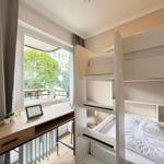 Zimmer mit Doppelstockbett, Schreibtisch und Balkonblick.