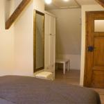 Schlafzimmer mit Bett, Kleiderschrank und Holztür