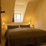 Schlafzimmer mit Dachfenster, Bett, Nachttischen und Lampen.
