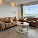 Wohnzimmer mit braunen Sofas, runden Tisch und Blick auf Balkon.
