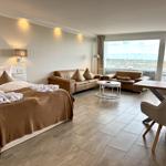 Ein Schlafzimmer mit Bett, Sofa, Tisch und Balkon mit Aussicht.