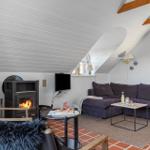 Wohnzimmer mit Kamin, Sofa und TV unter schrägem Dach