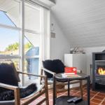 Zwei Sessel mit Fellkissen, Kamin und großes Fenster mit Blick auf Außenbereich.