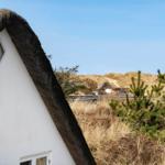 Dorfhaus mit Strohdach, Blick auf Dünen und weitere Häuser