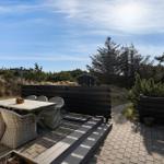 Terrasse mit Tisch und Stühlen, Blick auf Grünflächen und Himmel.