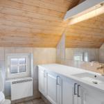 Badezimmer mit Holzdecke, Waschbecken, Spiegel und Toilette.