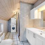 Badezimmer mit Waschmaschine, Toilette und Spiegelschrank.