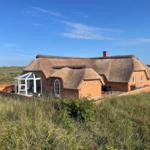 Haus mit Strohdach und Glasveranda in Grasland