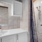 Badezimmer mit Dusche, Waschbecken und Spiegel.