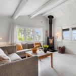 Wohnzimmer mit Sofa, Kamin und Fenstern zum Meer
