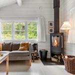 Ein Wohnzimmer mit Sofa, Kamin und Fenstern zum Blick auf die Natur.