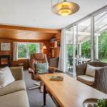 Wohnzimmer mit Sofa, Sessel und Tisch. Durchgang zu Terrasse mit Gartenansicht.