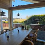 Esszimmer mit Holztisch, Stühlen und Blick auf Garten und Feld.