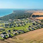 Aerial view of a coastal holiday park with cabins, trailers, and surrounding fields.