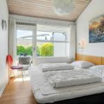 Schlafzimmer mit Bett, Fenster und roter Stuhlecke.