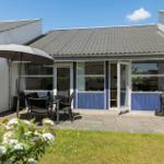 Terrasse mit Tisch, Stühlen und Sonnenschirm. Hinterhof mit Gras und Gartenmöbeln.