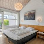 Schlafzimmer mit Doppelbett, Fenster und Balkon. Holzdecke und Wandkunst.