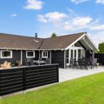 Schwarzes Holzhaus mit Terrasse und Garten. Außentisch und Stühle für Gäste.